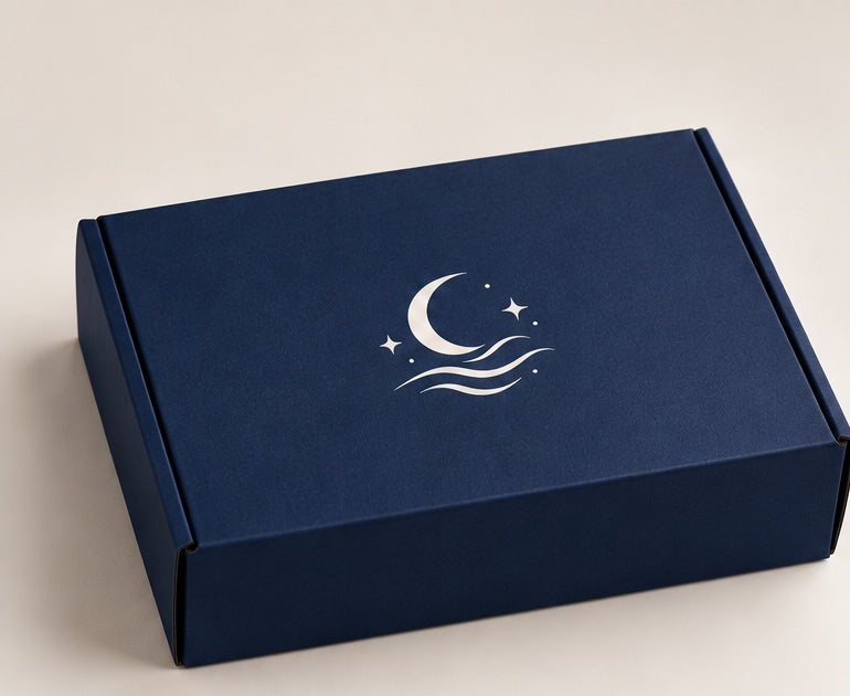 The navy Moon Tide mailer box closed, with the Moon Tide moon and waves logo